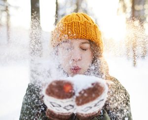 Frau pustet Schnee von Ihren Händen